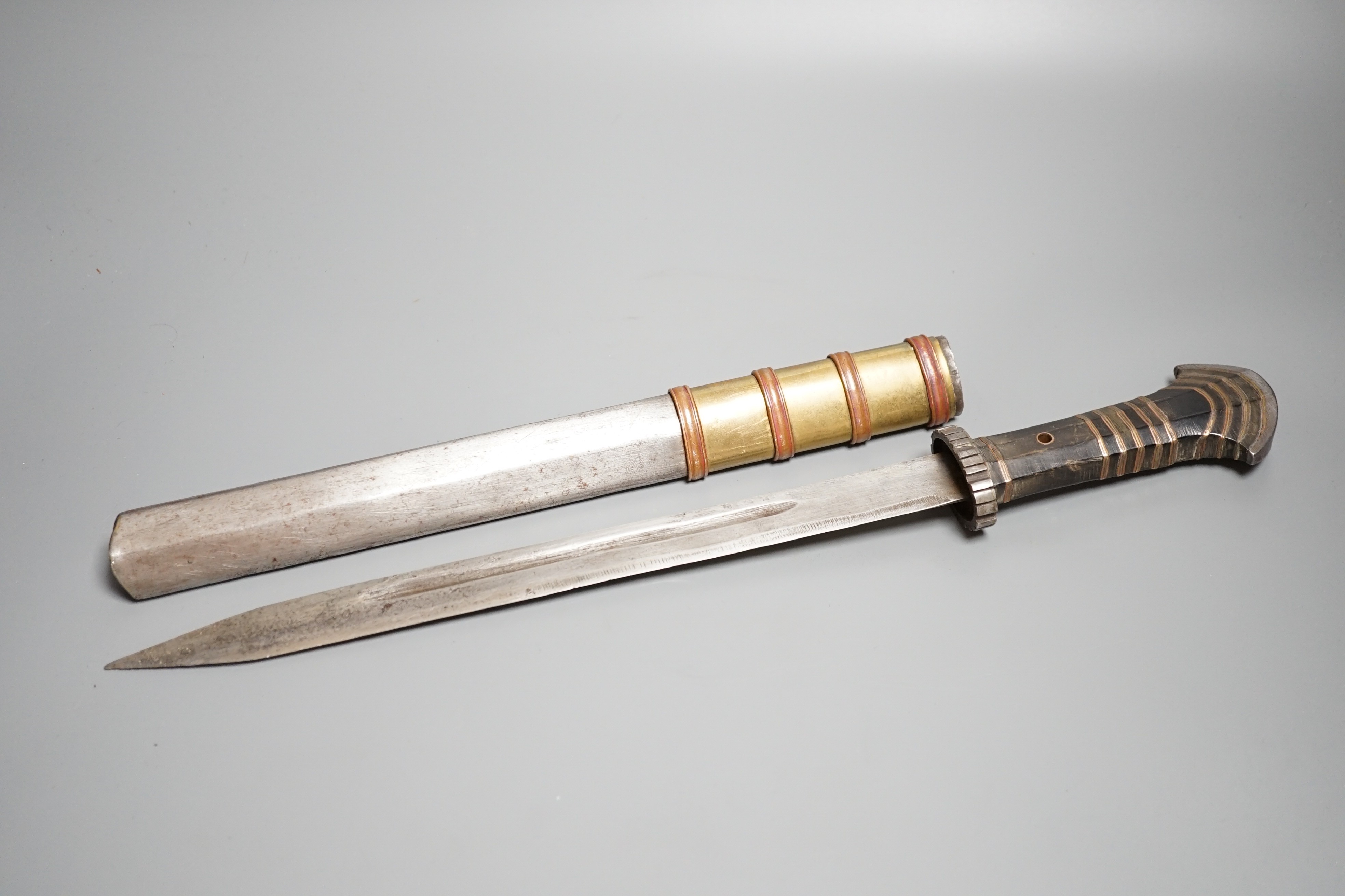 A large Tibetan dagger, early 20th century, horn handle with layers of copper and brass, iron pommel, guard and sheath with copper and brass mounts, length 46cms